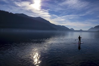 Man on a Paddleboard on Lake Lugano with Sunlight and Mountain in Ticino, Switzerland, Europe