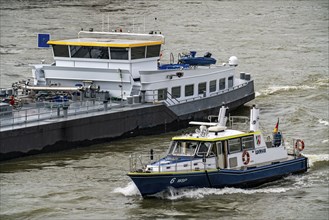 Water police boat, on the Rhine, next to a cargo ship, Cologne North Rhine-Westphalia, Germany,