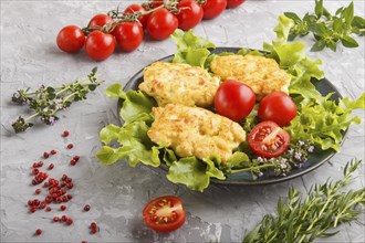 Minced chicken cutlets with lettuce, tomatoes and herbs on a gray concrete background. side view,