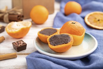 Truffle chocolate tangerine candies on a white wooden background and blue linen textile. Side view,