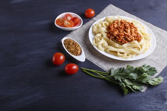 Fettuccine bolognese pasta with minced meat on black wooden background. close up, copy space