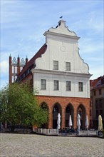 Historic gabled house on a cobbled town square with closed parasols and a tree, Old Town Hall on