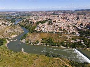 Panoramic view of a city with a river and several bridges, surrounded by hills and many houses,