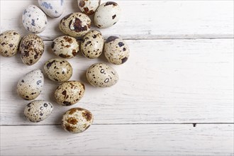 Raw quail eggs on a white wooden background, top view