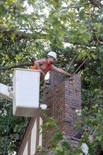 Detroit, Michigan, A worker dismantles a brick chimney after a storm with 70mph wind gusts blew