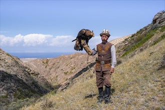 Traditional Kyrgyz eagle hunter with eagle in the mountains, near Kysyl-Suu, Kyrgyzstan, Asia