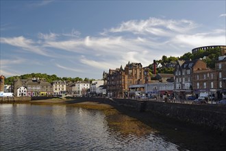 Coastal town with historic buildings along a harbour under a clear sky with some clouds, harbour