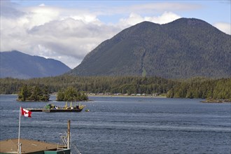 Canadian flag flying by the sea, small islands and mountains, Tofino, Vancouver Island, Canada,