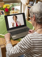 Symbolic image of telemedicine, patient speaking to a doctor in a video conference from home