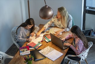 Homeschooling, during the lockdown in January 2021, mother helps her two daughters, at home,