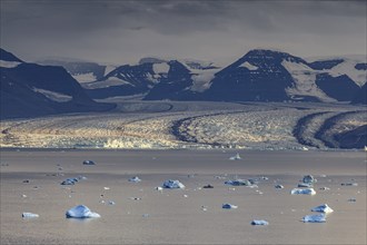 Evening mood with clouds over a glacier, glacier tongue, fjord with icebergs in front of mountains,