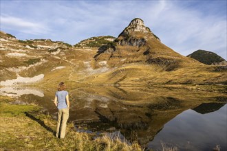 Lake Augstsee and the Atterkogel mountain on the Loser. A hiker stands on the shore. Autumn, good