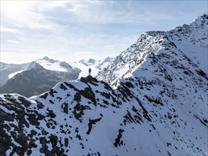 Mountaineer standing on the snow-covered Ramoljoch under a clear sky in the Alps, behind glacier