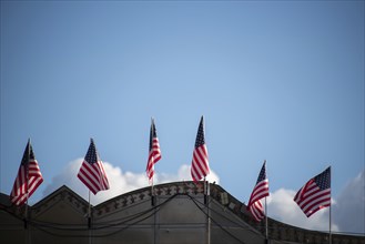 Row of American flags waving in the wind at a fairground stand under a blue sky, Magdeburg,