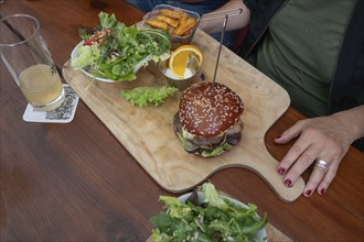 Veggie burger with fries and salad served on a wooden board, Bavaria, Germany, Europe