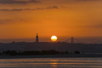 A sunset over a city by the sea with a striking statue and a bridge in the background, Statue