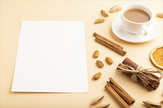 Composition with white paper sheet, almonds, cinnamon and cup of coffee. mockup on orange