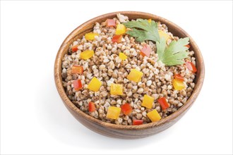 Buckwheat porridge with vegetables in wooden bowl isolated on white background. Side view, close up