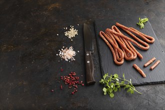 Traditional polish smoked pork sausage kabanos on a slate cutting board with salt and pepper on