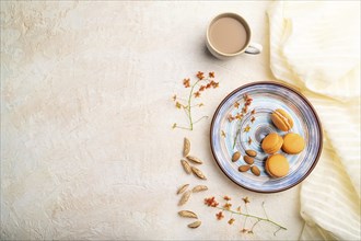 Orange macarons or macaroons cakes with cup of coffee on a white concrete background and linen