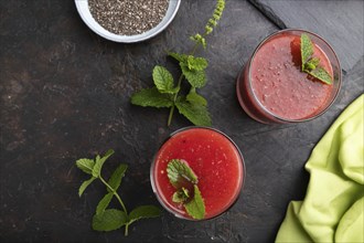 Watermelon juice with chia seeds and mint in glass on a black concrete background with green