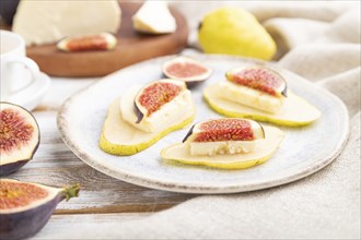 Summer appetizer with pear, cottage cheese, figs and honey on a white wooden background and linen