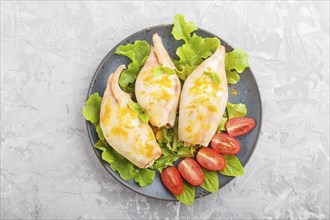 Stuffed baked squid with greens on a blue ceramic plate on a gray concrete background, top view,