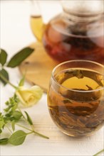 Red tea with herbs in glass teapot on white wooden background. Healthy drink concept. Top view,