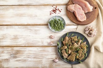 Stewed turkey fillet with garlic and sprouts of green peas on white wooden background and linen