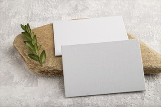 White paper business card, mockup with natural stone and boxwood branch on gray concrete background