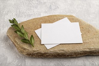 White paper business card, mockup with natural stone and boxwood branch on gray concrete background