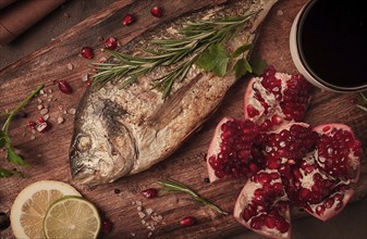 Fried dorado fish, with spices and herbs, on a wooden board, pomegranate sauce, close-up, no people