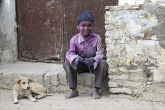 Child with dog covered in pink dye celebrating the Holi festival, Festival of Colours in Vrindavan,