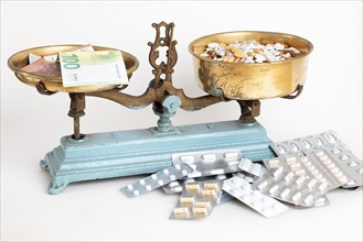 Old scales with medicines and euro banknotes facing each other, white background