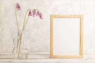 Wooden frame with pink dicentra, broken heart in glass on gray concrete background. side view, copy