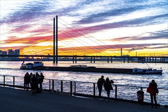 Winter sunset on the Rhine near Düsseldorf, riverside promenade at the old town, cargo ship,