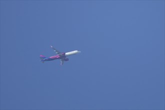 Airbus A320 aircraft of Wizz air airlines in flight across a blue sky, England, United Kingdom,