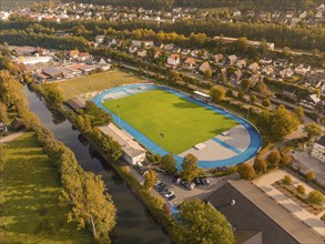 Aerial view of a stadium with a blue running track, surrounded by residential buildings and a