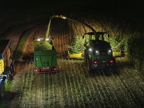 Tractors harvesting a field at night, trailers being filled, maize harvest, Dachtel, Black Forest,