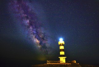 Radiant lighthouse under the night sky, illuminated by the Milky Way and stars, Colonia St. Jordi,