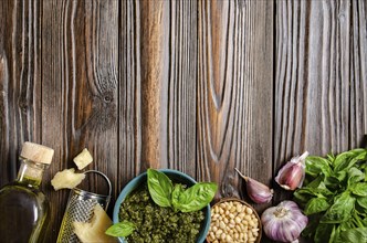 Flat lay food background of genovese pesto sauce and its ingredients on wooden kitchen table with