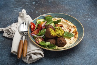 Close up of Middle Eastern Arab meal with fried falafel, hummus, vegetables salad with fresh green