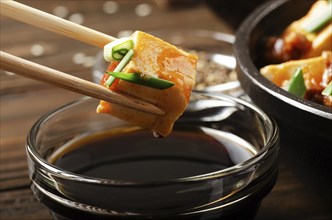 Mapo tofu dish of soybean curd piece being held in chopsticks