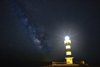 Lighthouse illuminated under a twinkling starry sky with the Milky Way in the background, Colonia