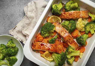 Top view close up of healthy baked fish salmon steaks, broccoli, cauliflower, carrot in casserole