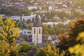 Town church tower at dusk, surrounded by autumnal trees and houses, Nagold, Black Forest, Germany,