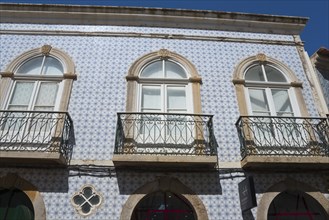 Facade of a house with blue azulejos and wrought-iron balconies in traditional Portuguese style,