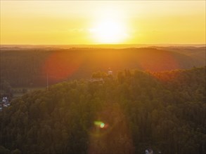 View of wooded hills at sunset, the sky coloured in warm orange tones, Nagold, Black Forest,