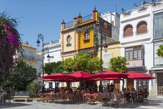 Cosy pavement café with red parasols in a historic square, Plaza del Cabildo, Sanlúcar de