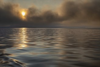 Sun breaking through clouds, reflection on slightly wavy sea surface, Woodfjord, Svalbard and Jan